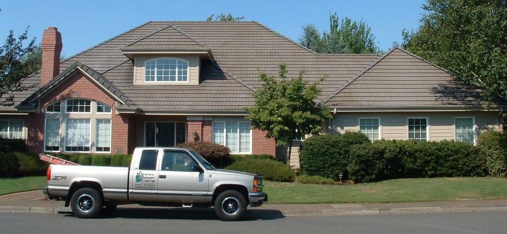 Silver pickup truck parked in front of a large suburban home with a well-maintained lawn.